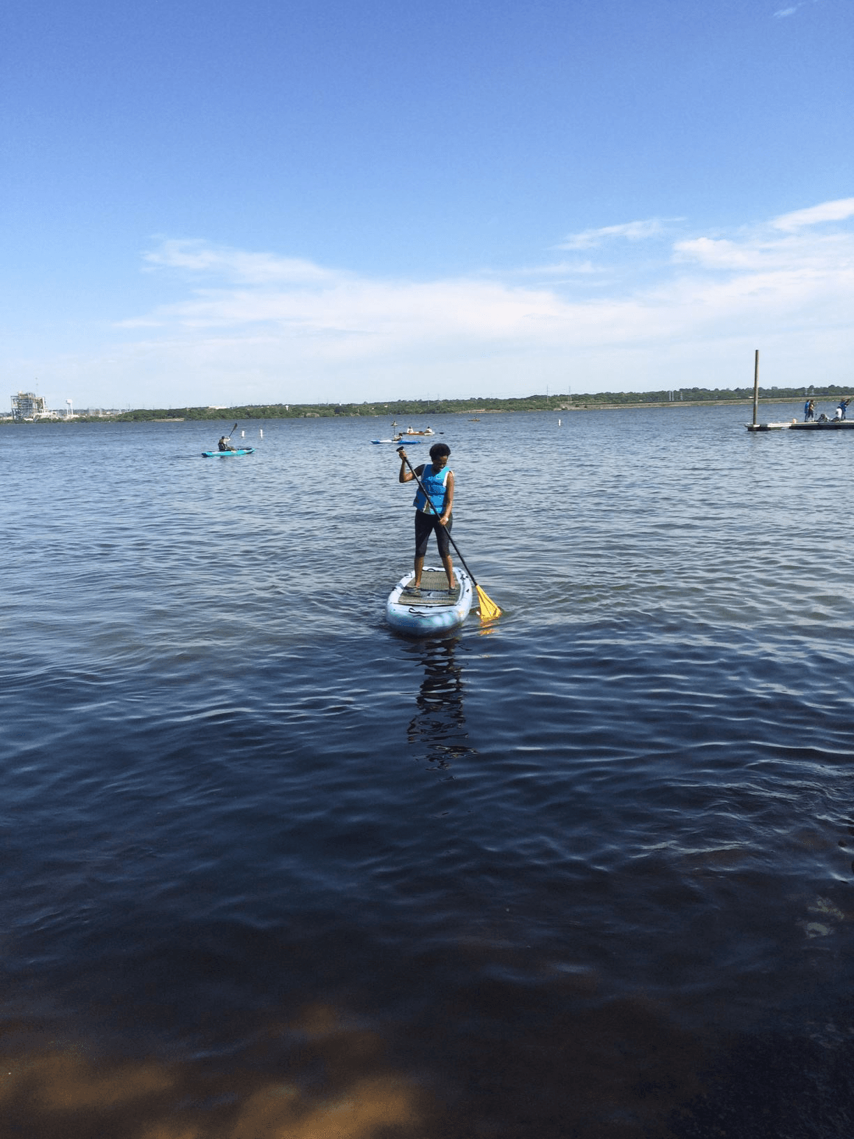 Stand-up paddleboarder balancing and paddling on calm bay water