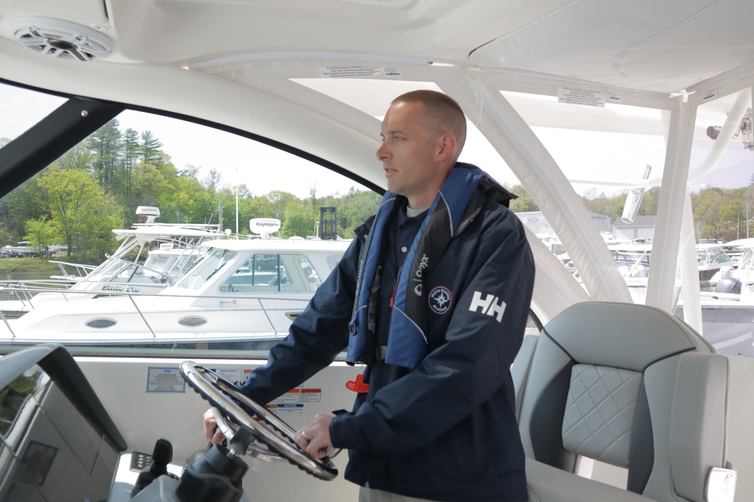 Instructor piloting boat from helm, teaching navigation near marina