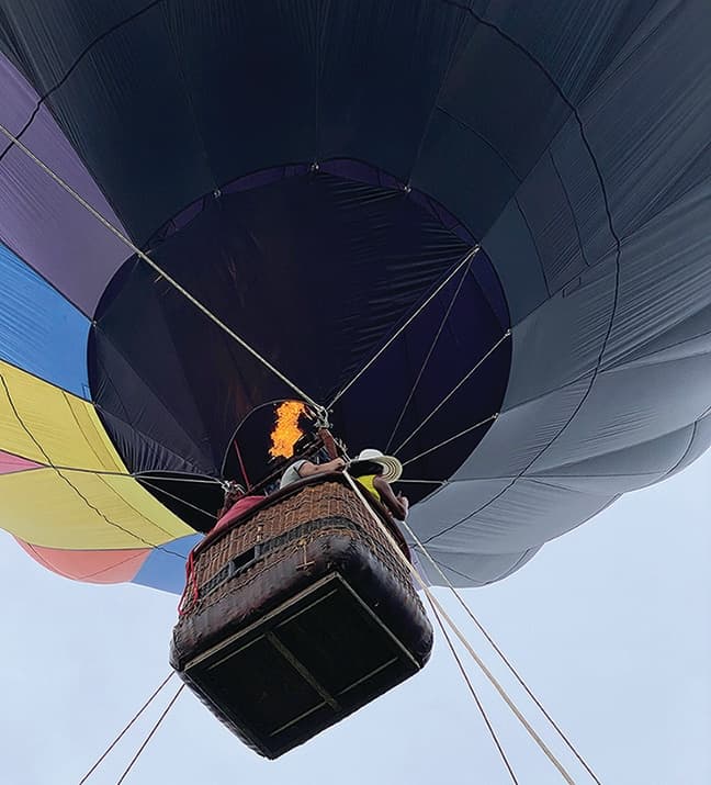 Close-up hot air balloon basket inflating skyward from below