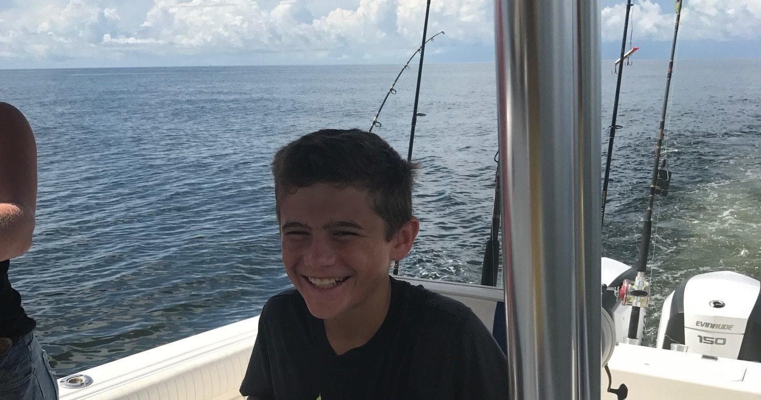 Teen angler smiling on fishing charter boat with ocean view