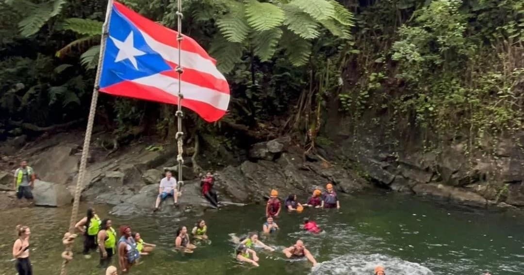People swimming and rope-swinging at Puerto Rico jungle river pool