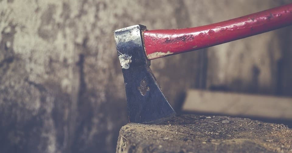 Red-handled axe stuck in wood stump in rustic cabin setting