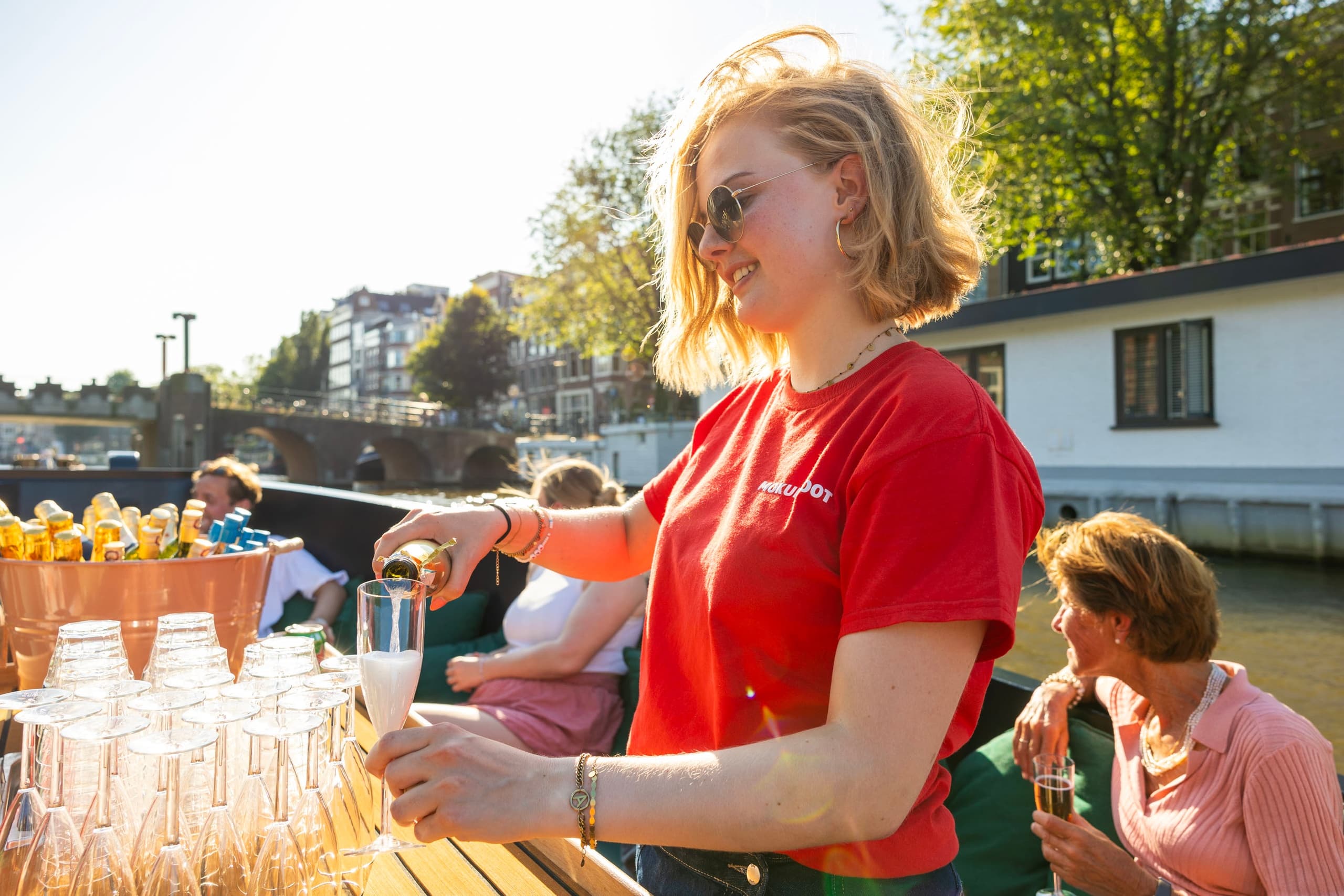 On-deck bartender serving drinks during Amsterdam canal cruise