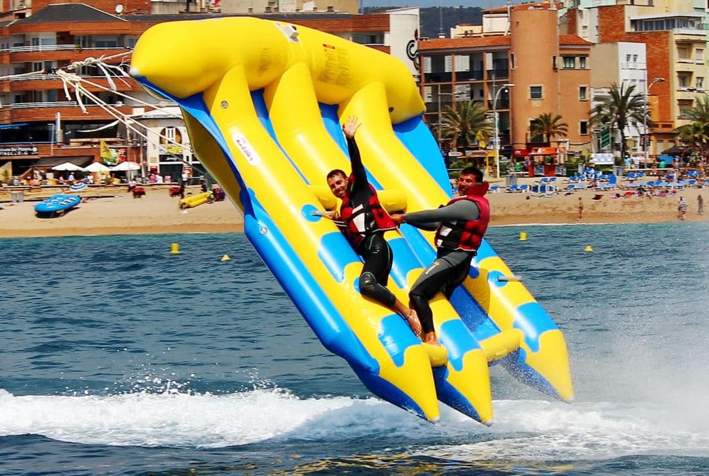 Extreme airborne banana boat jump with riders off coastal resort waters