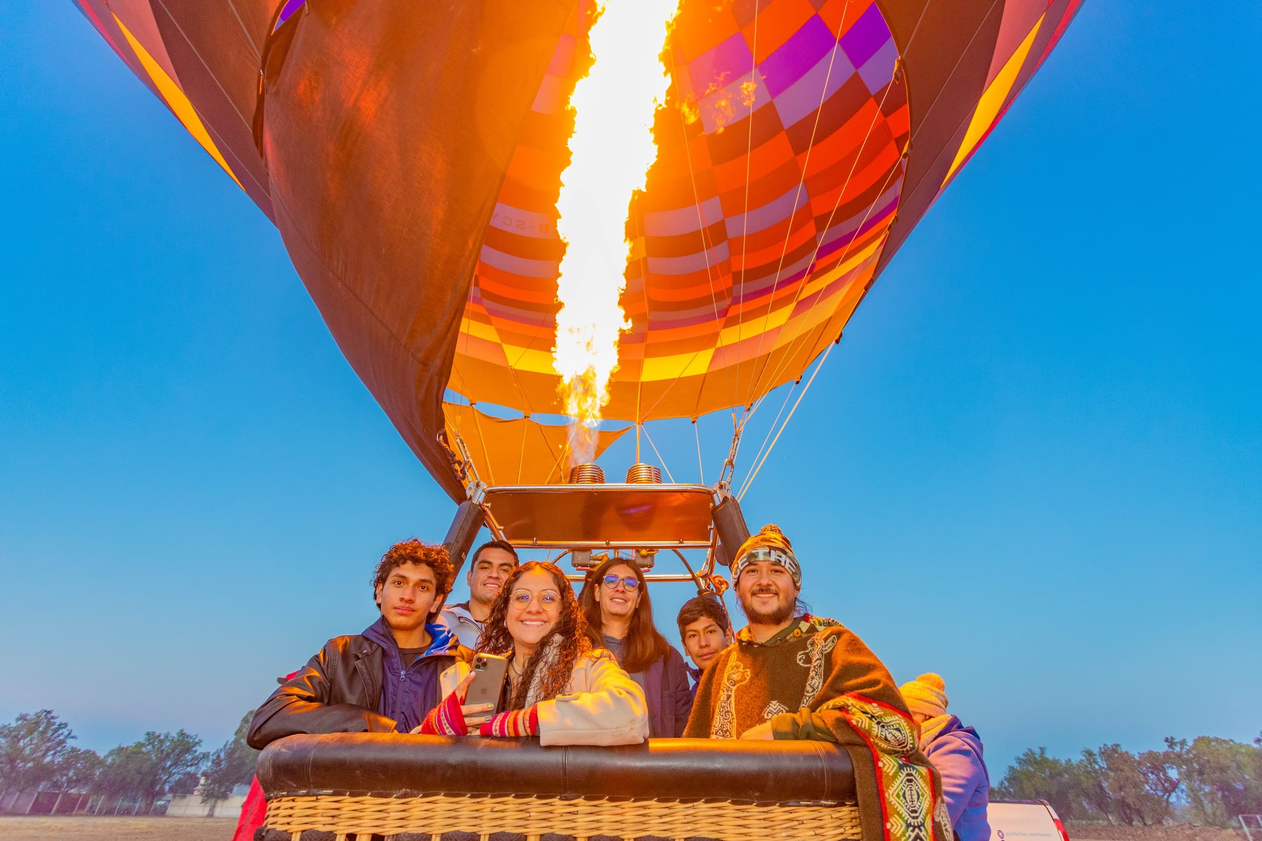 Friends riding in a hot air balloon basket under burner flame