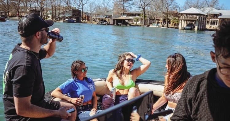 Group of friends boating on Lake Austin, relaxing and drinking outdoors