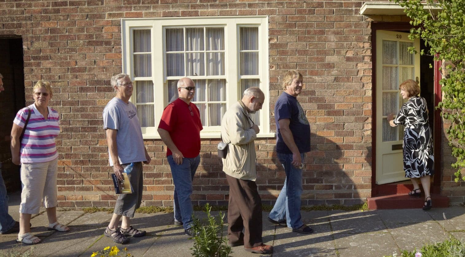 People queuing outside residential home during guided city tour