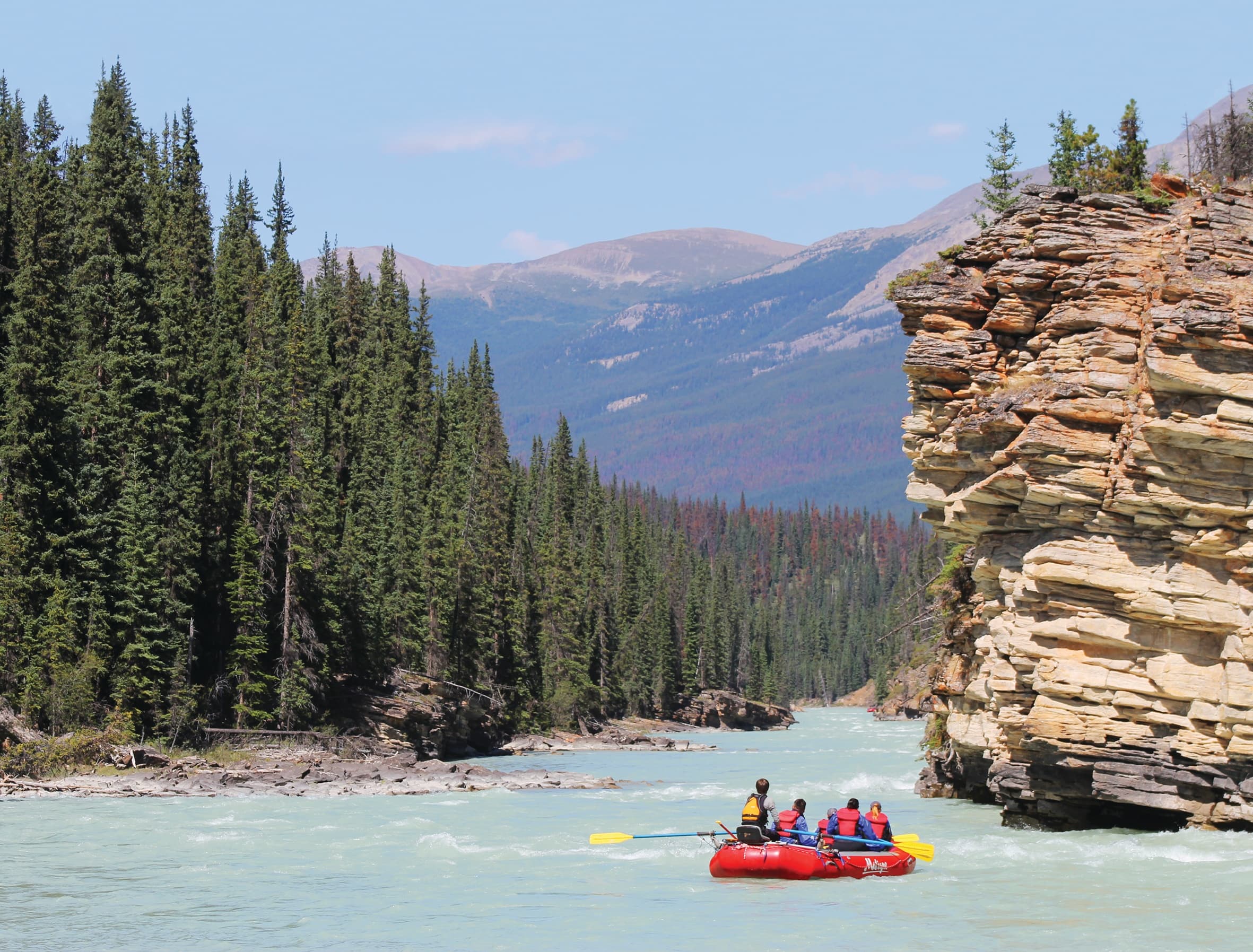 Rafting group paddling through canyon on turquoise mountain river