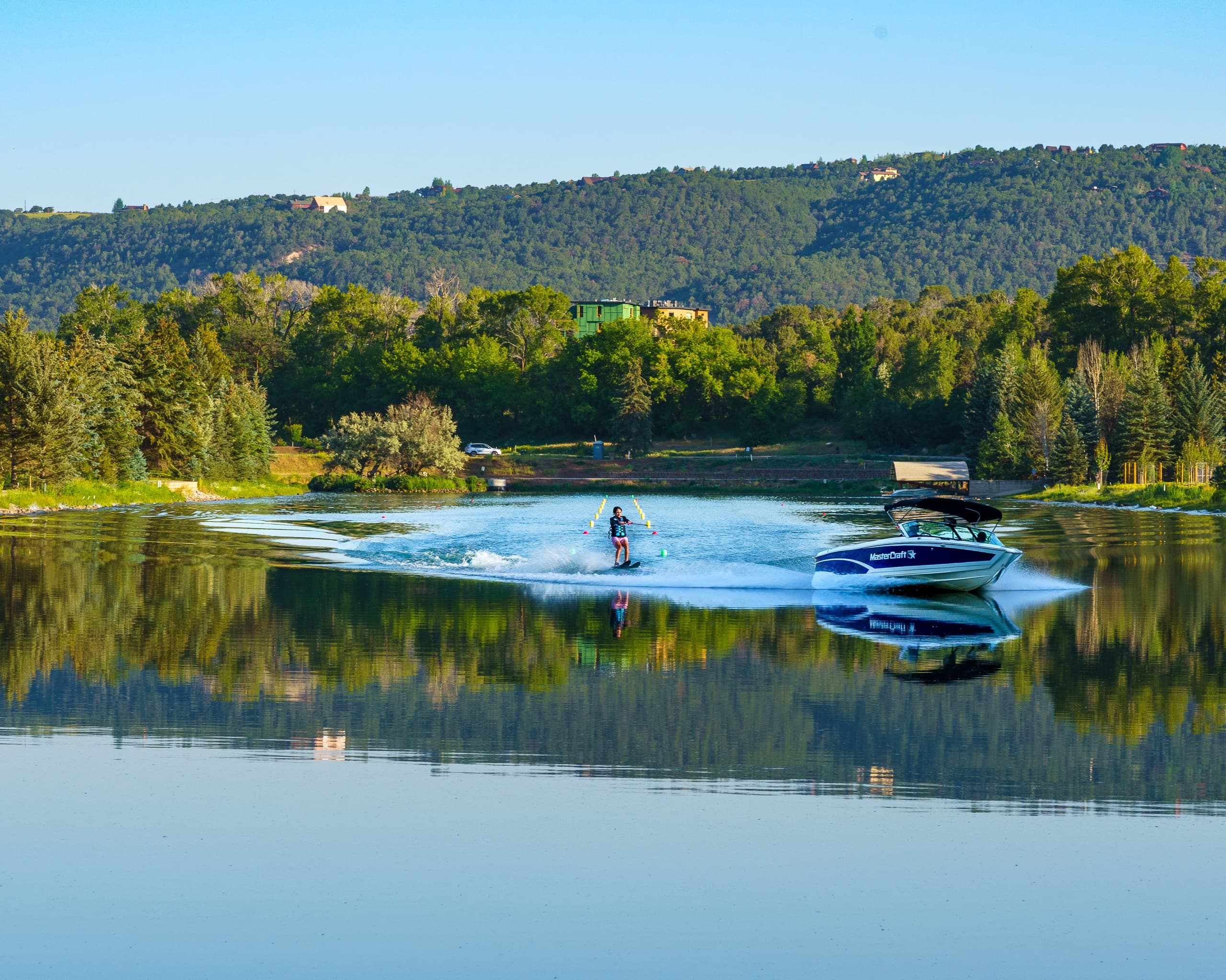 Waterskier towed by speedboat on a calm forested mountain lake