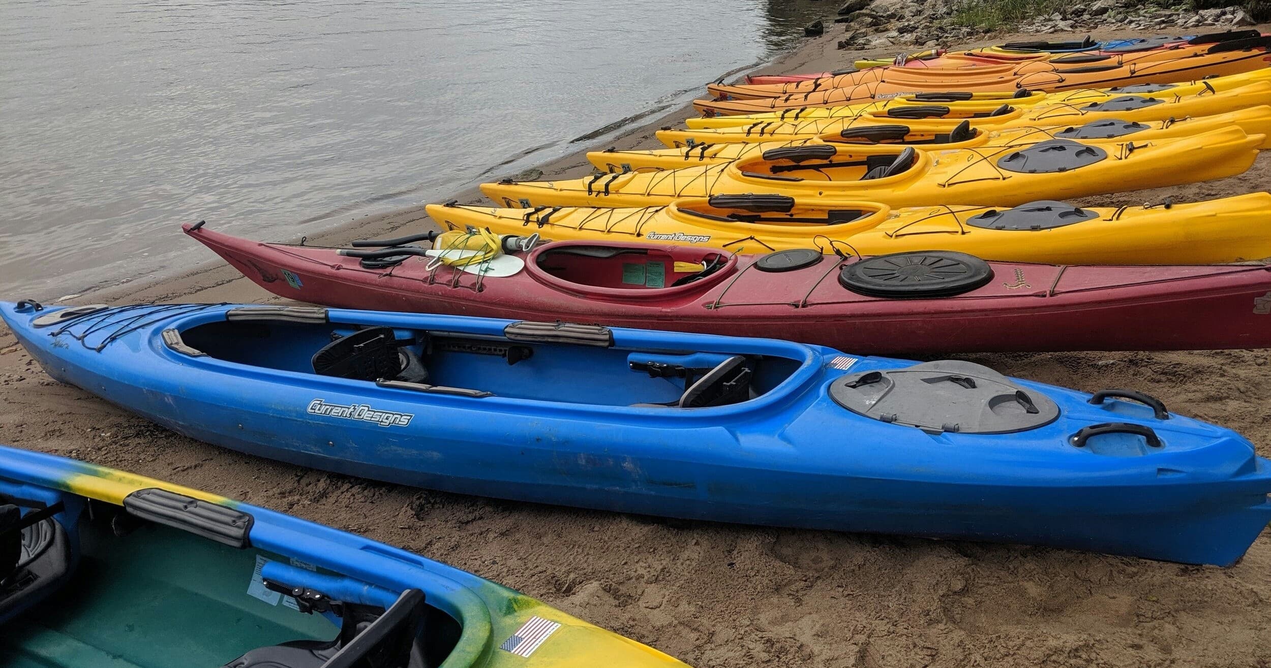 Colorful kayaks lined up on shoreline ready for guided tour