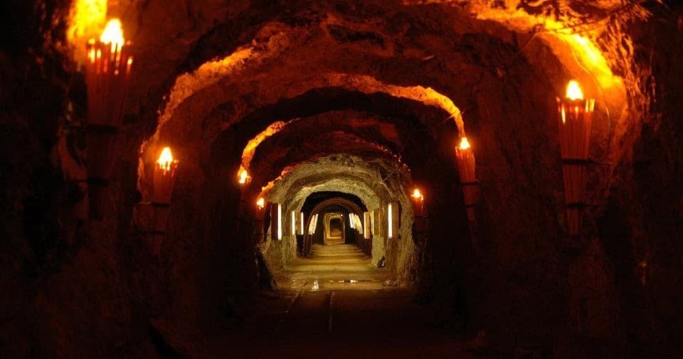 Torchlit underground silver mine tunnel showcasing historic passage