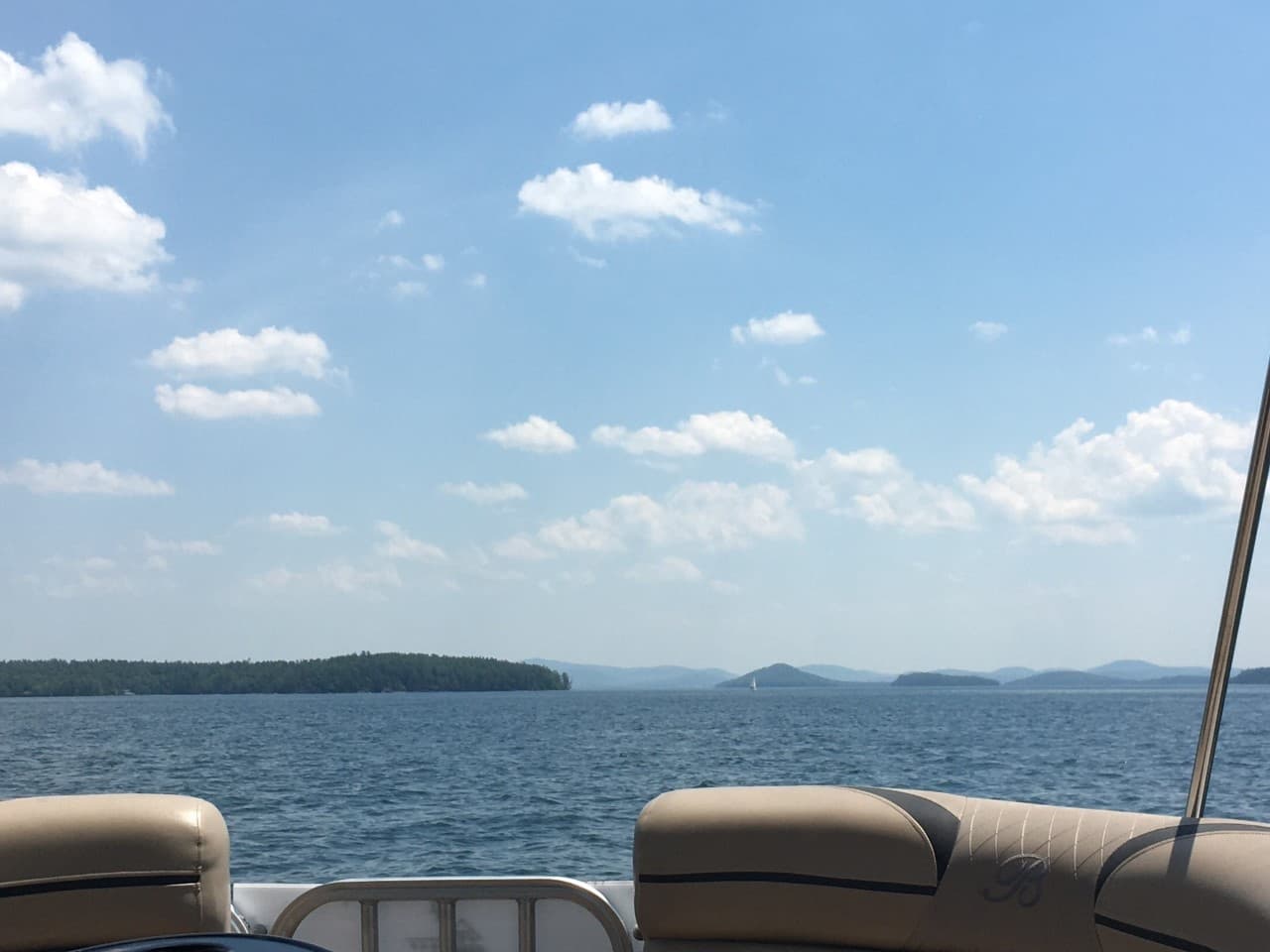 Pontoon boat deck overlooking expansive forested lake horizon
