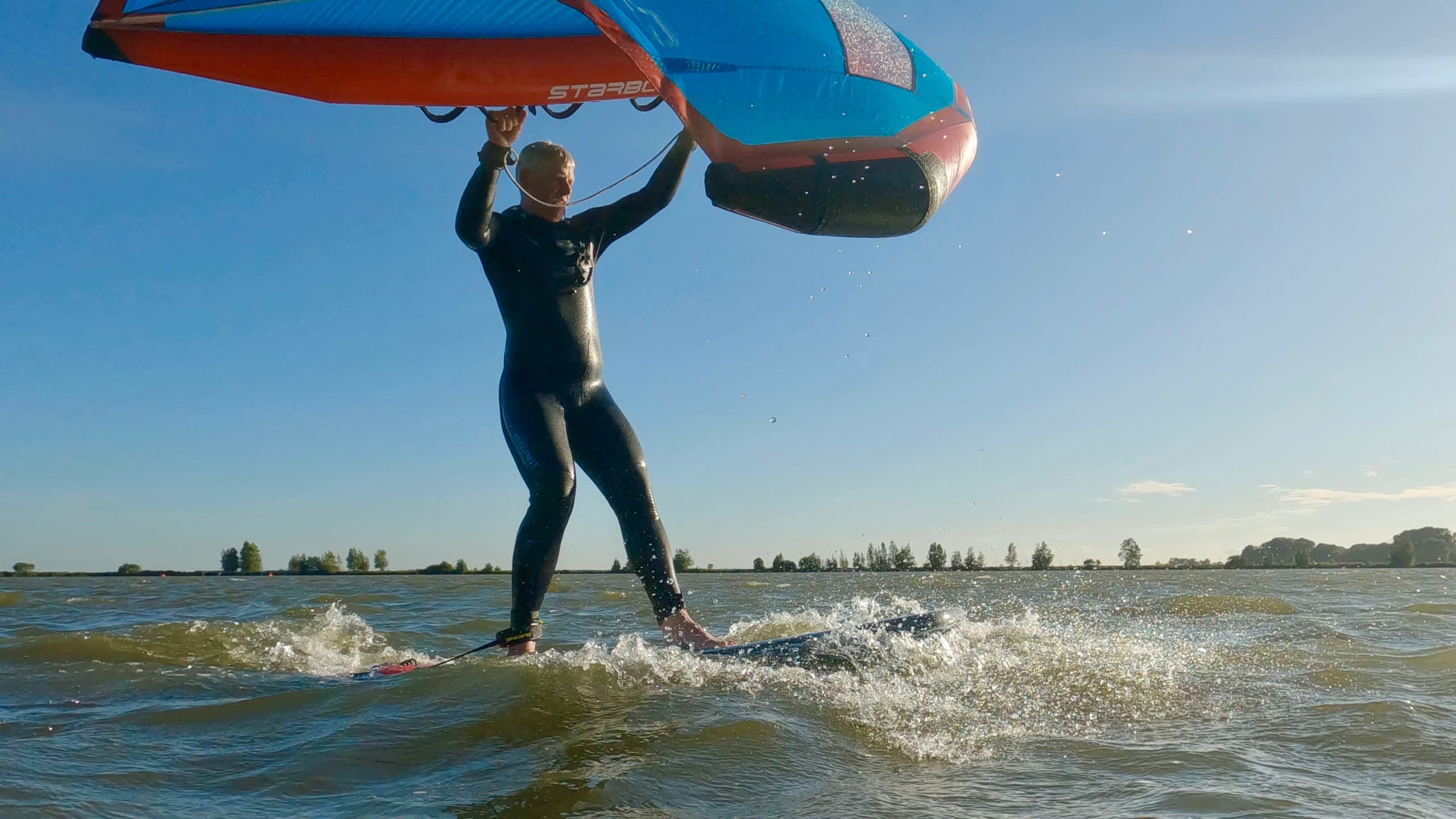 Wingfoil rider jumping over waves on coastal waters