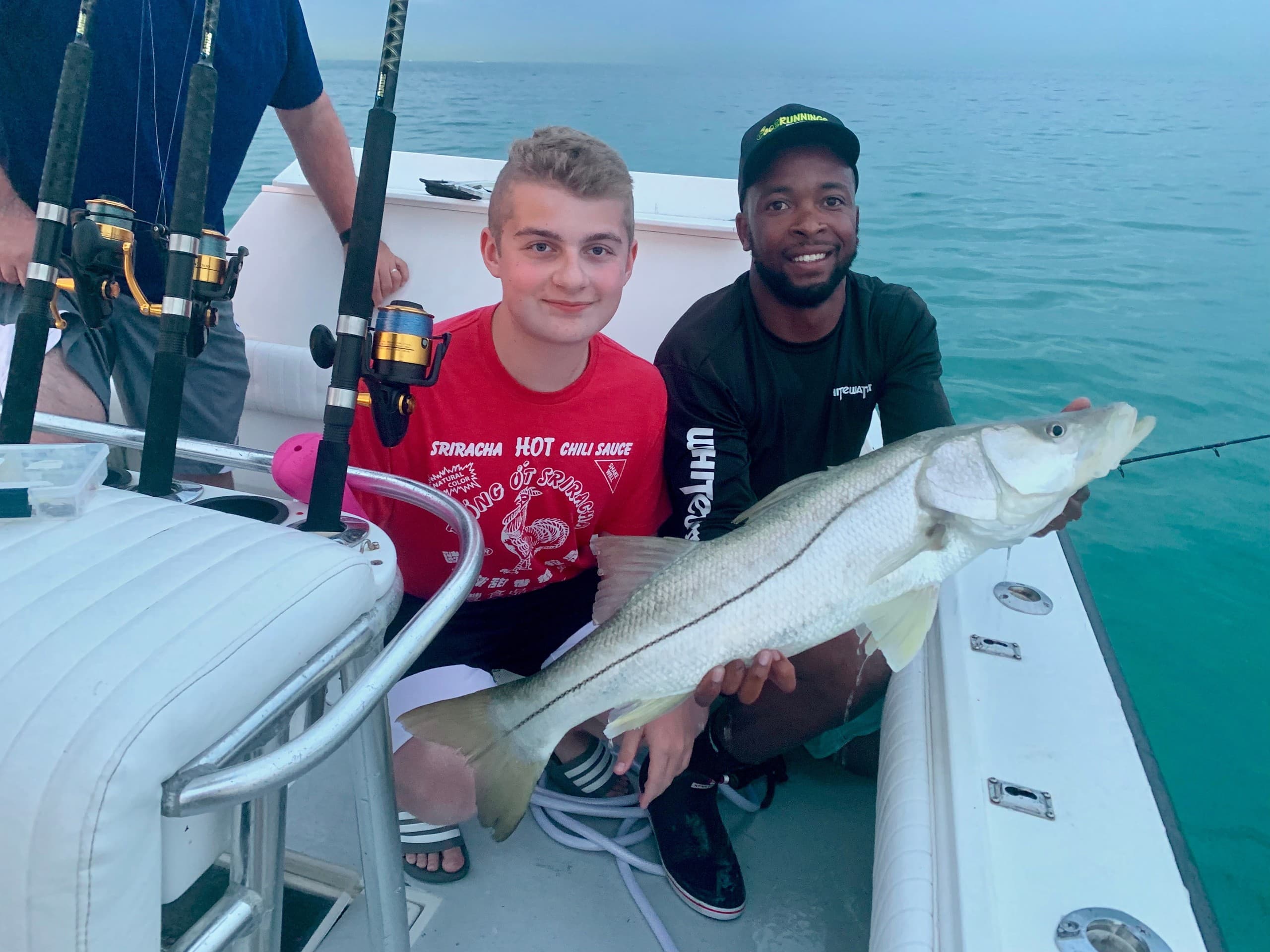 Two anglers showing trophy fish on charter boat near reef