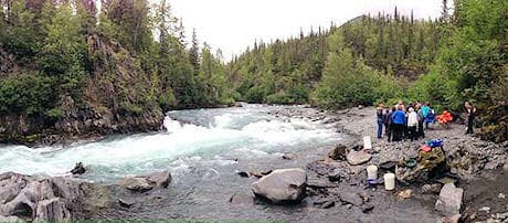 Group by rushing Alaskan river during outdoor adventure tour