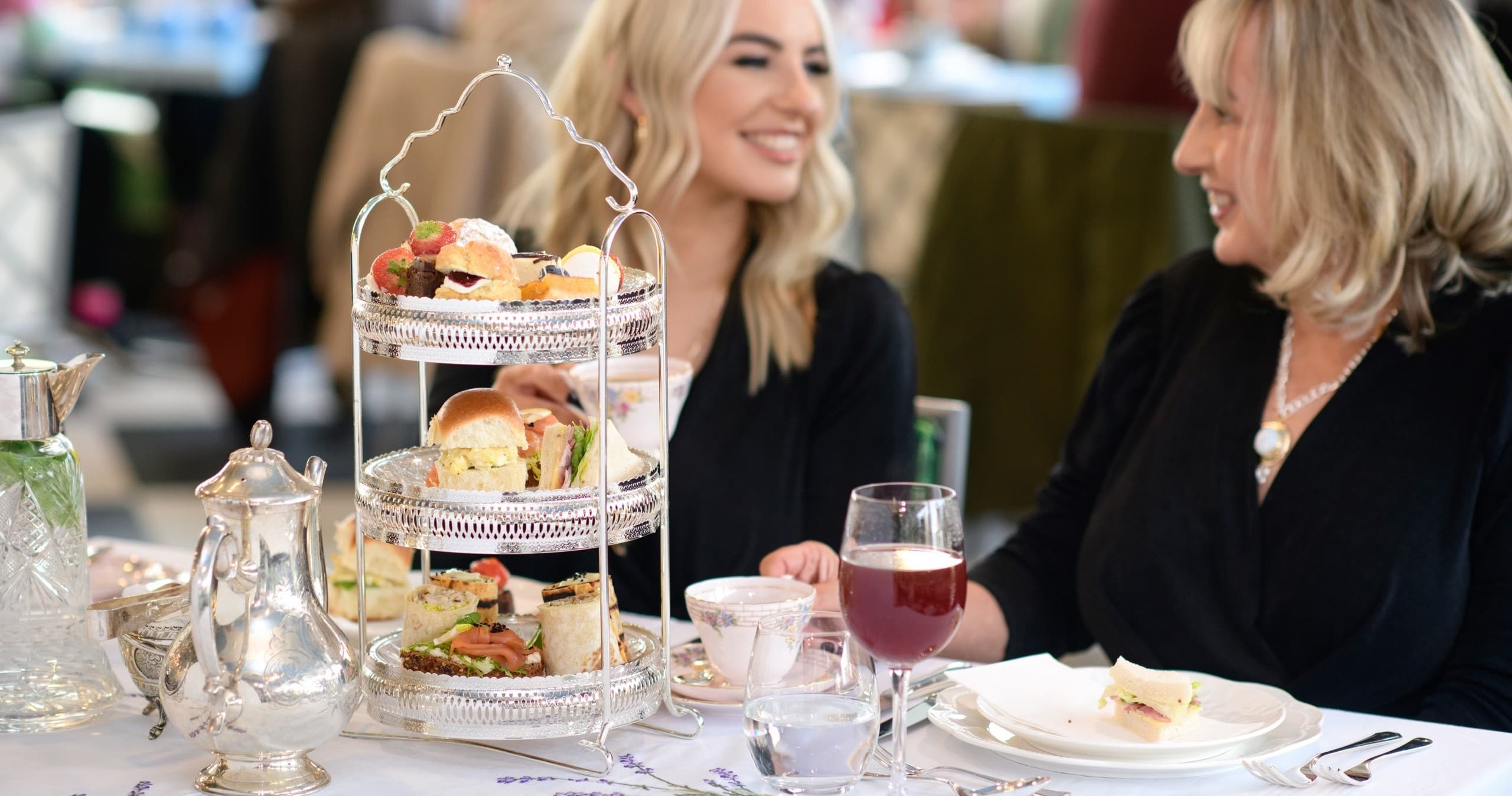 Two women enjoying afternoon tea with tiered cake stand