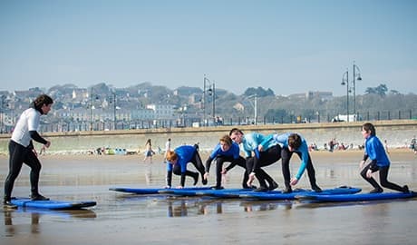 Surf lesson group practicing on shore with instructor and boards