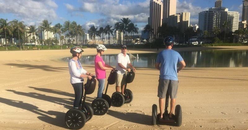 Guided Segway tour on sandy waterfront with city skyline view