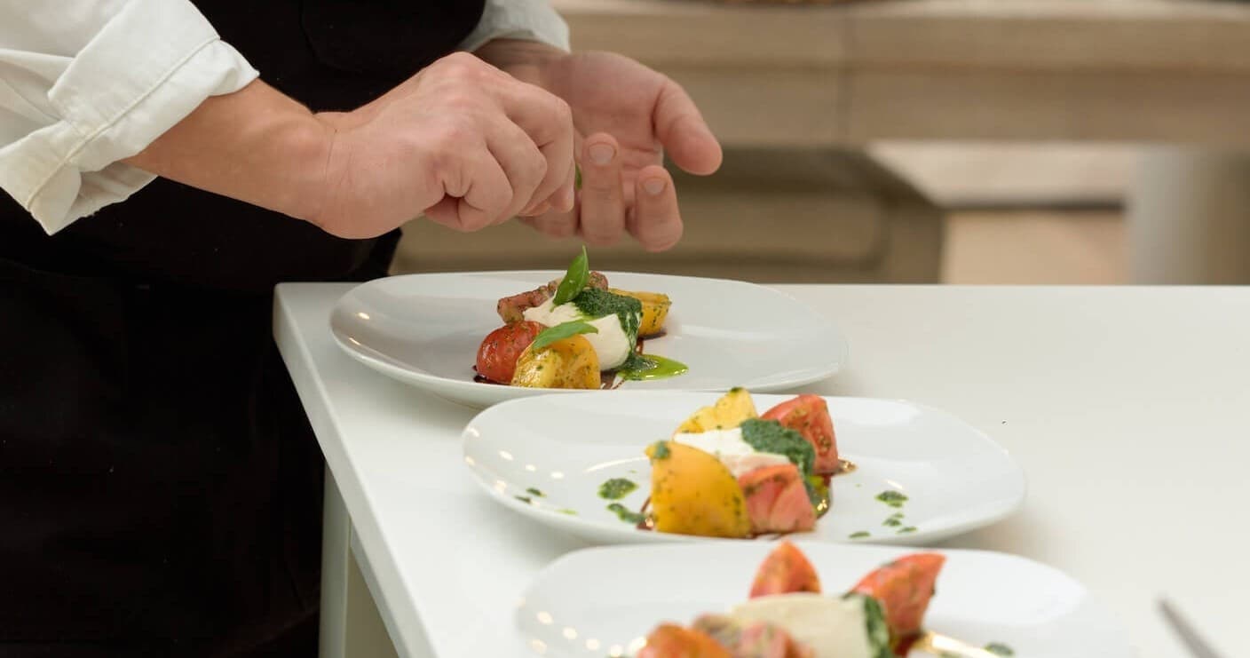 Chef plating gourmet dishes in yacht galley during private charter