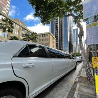 White stretch limousine parked on urban street beside downtown skyscrapers