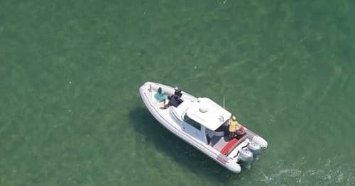 Overhead view of a small fishing boat cruising calm green water