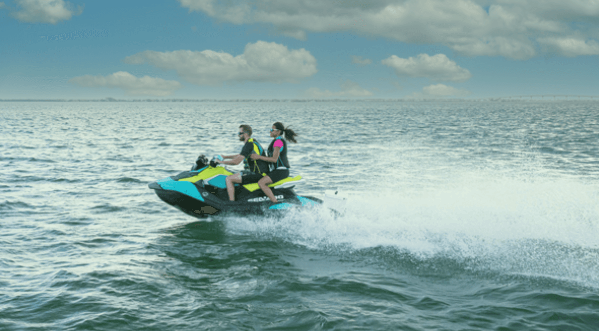 Two riders jet skiing across open ocean with cloudy sky