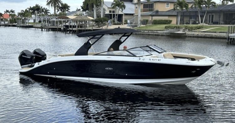 Sleek bowrider boat dockside in calm canal, marina backdrop