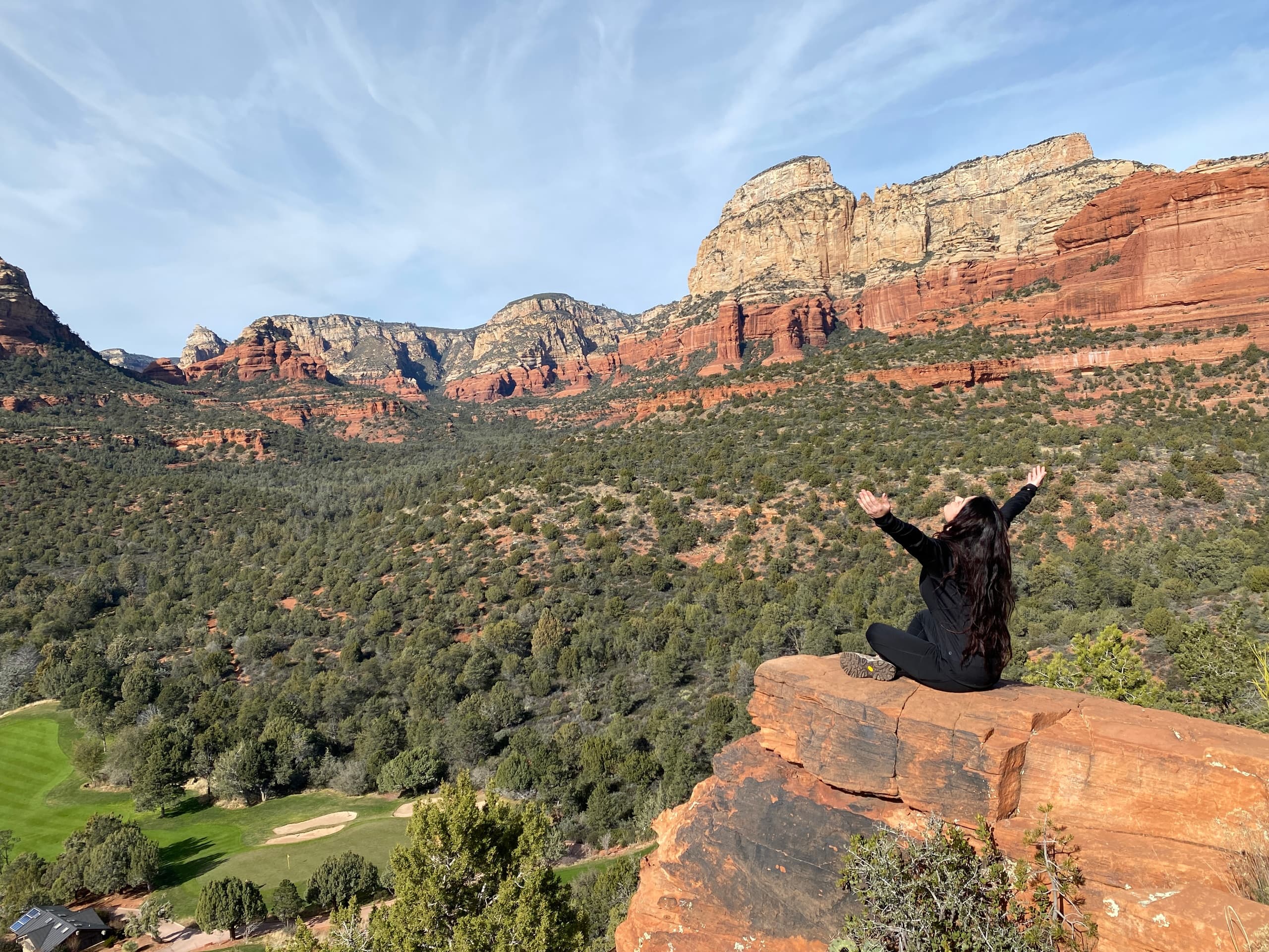 Hiker celebrating on sandstone overlook with valley views