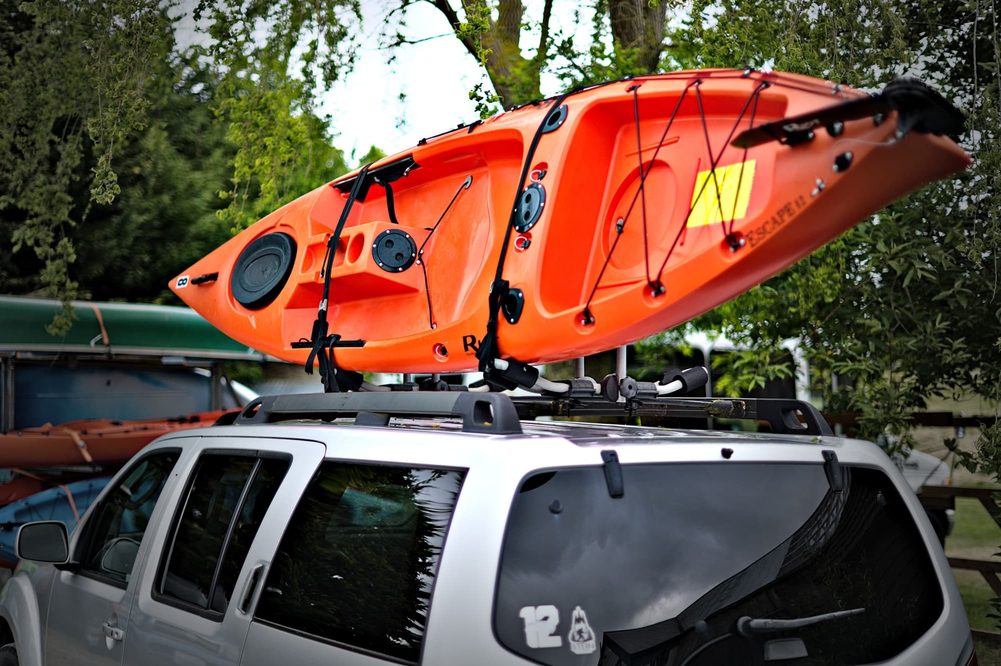 Orange kayak secured on vehicle roof rack ready for transport
