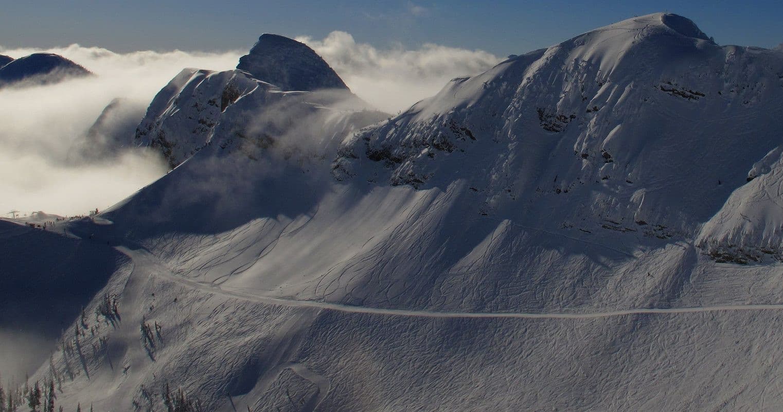 Snow-covered mountain ridge and alpine pass with dramatic clouds