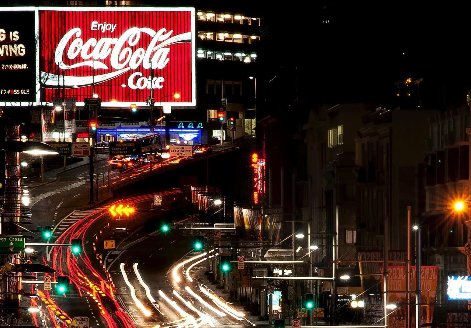 Night time city street with light trails and Coca Cola billboard