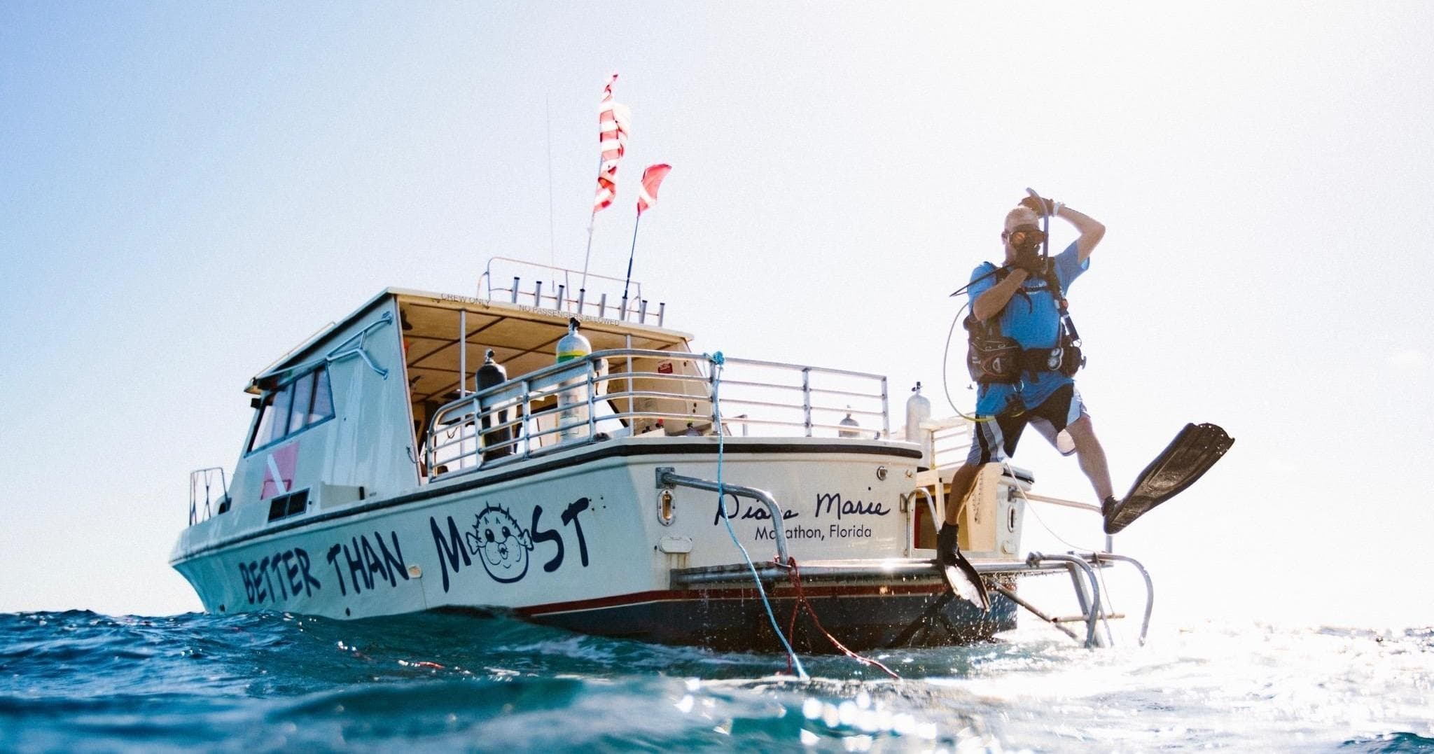Diver jumping off charter boat into bright tropical sea