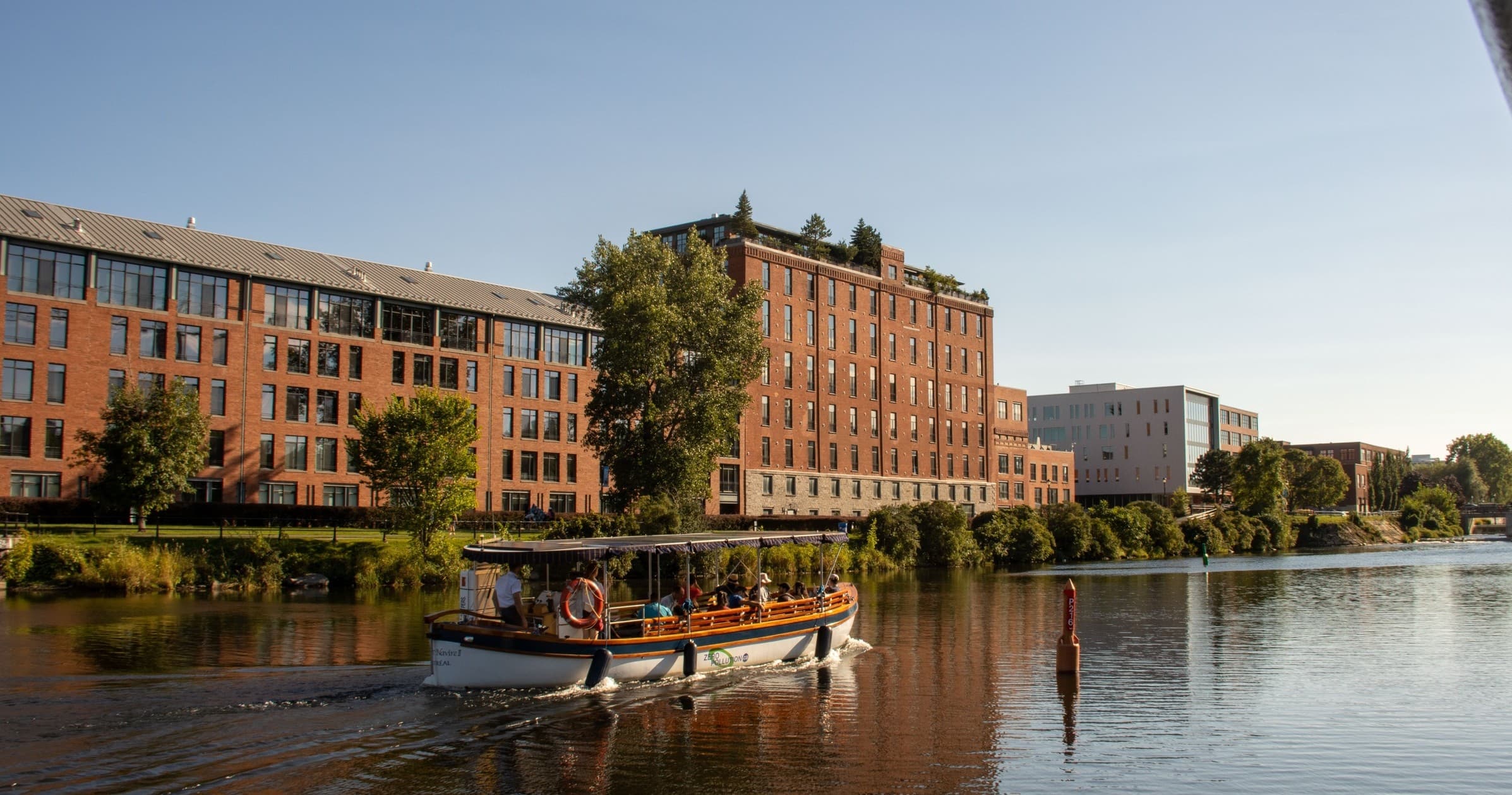 River sightseeing boat cruising past riverside brick warehouses