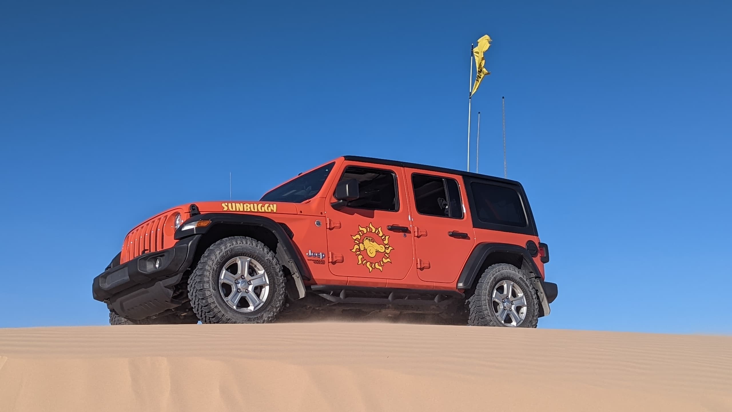 Jeep driving over sand dune at desert off-road tour