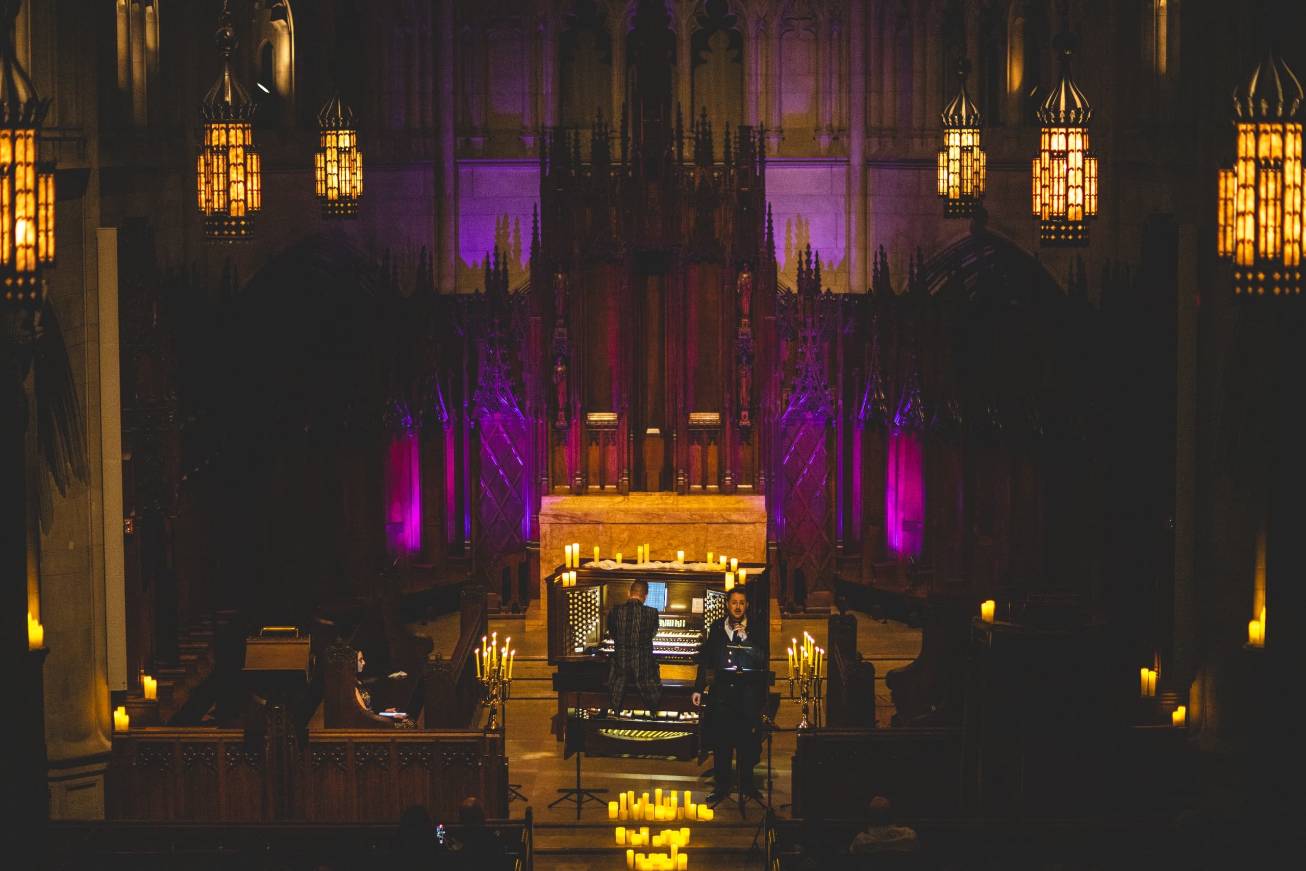 Ornate chapel interior with organ performance under purple lights