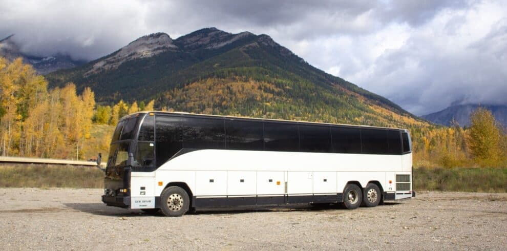 Tour coach parked with mountain backdrop and autumn colors