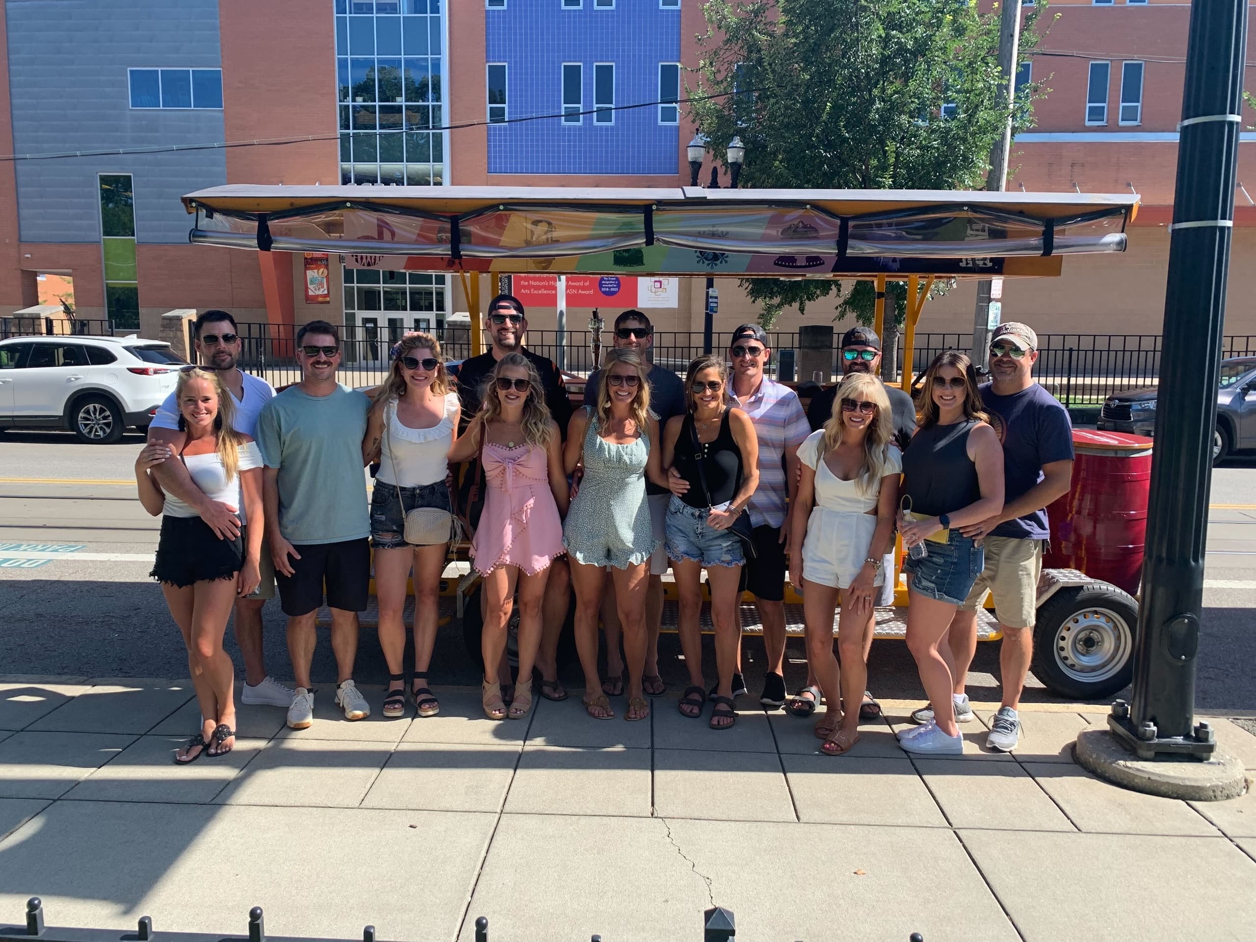 Sunlit group tour boarding Cincinnati pedal wagon on sidewalk