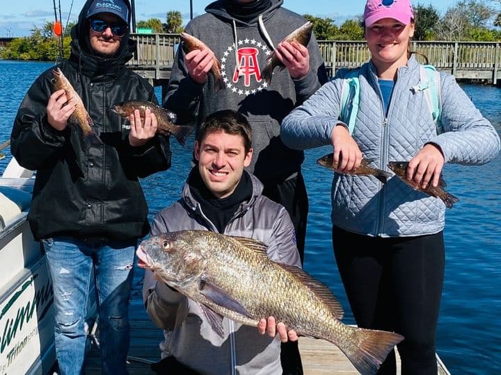 Anglers displaying a large fish on dock after fishing charter