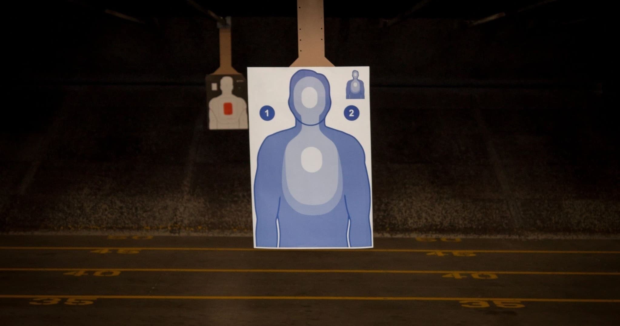 Hanging silhouette target at indoor firing range backstop for practice