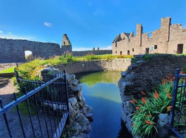 Stone castle ruins with moat and gardens at Dunnottar Castle