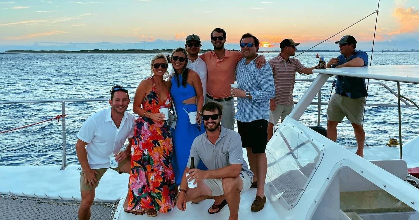Group enjoying sunset boat cruise on open ocean near coastline