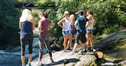Group of hikers standing on rocks by mountain stream on trail