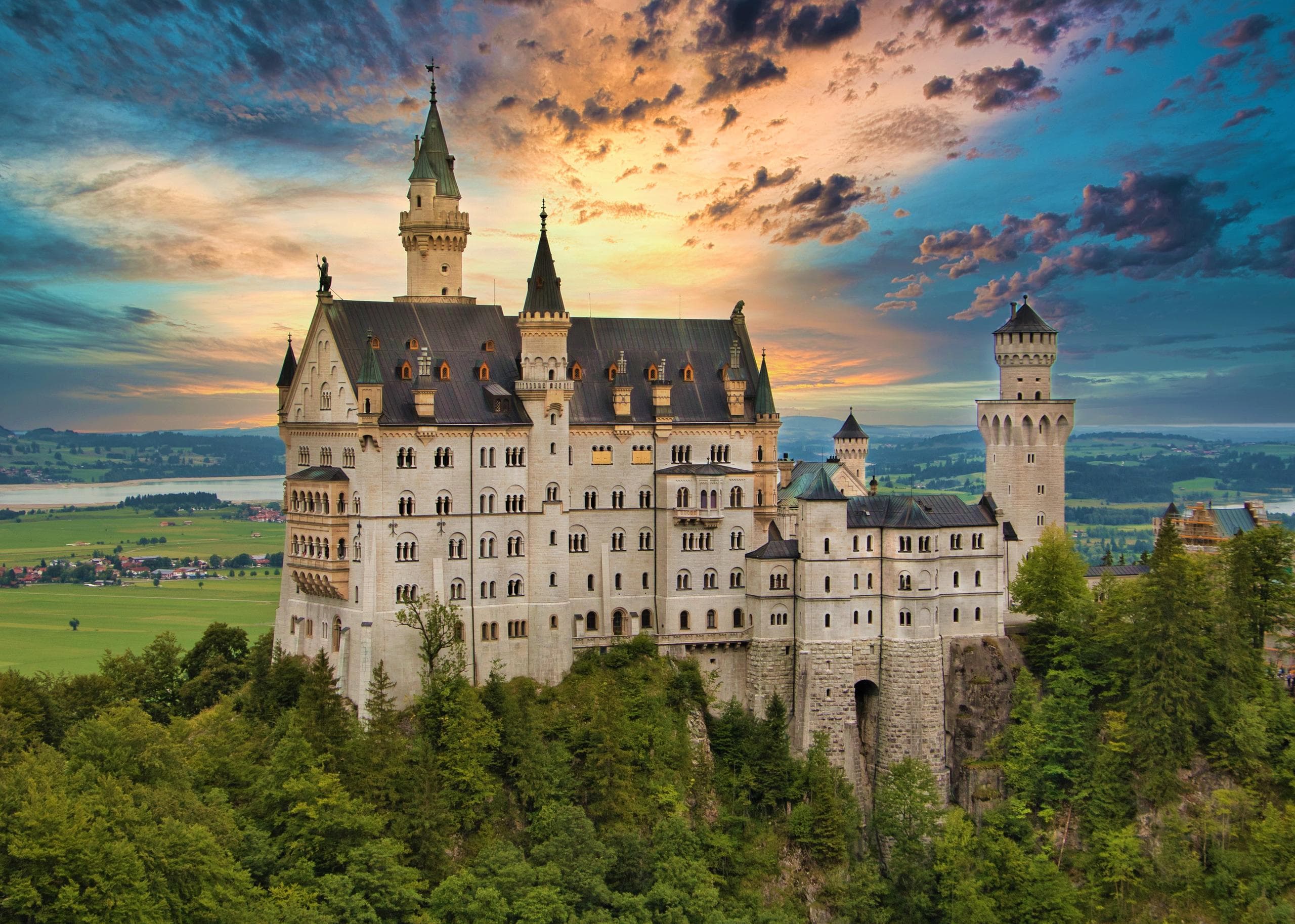 Neuschwanstein-style castle on hill at sunset, scenic viewpoint