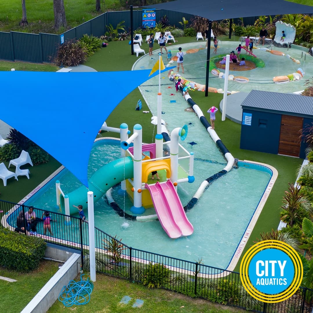 Kids on outdoor splash playground and slides at aquatic center