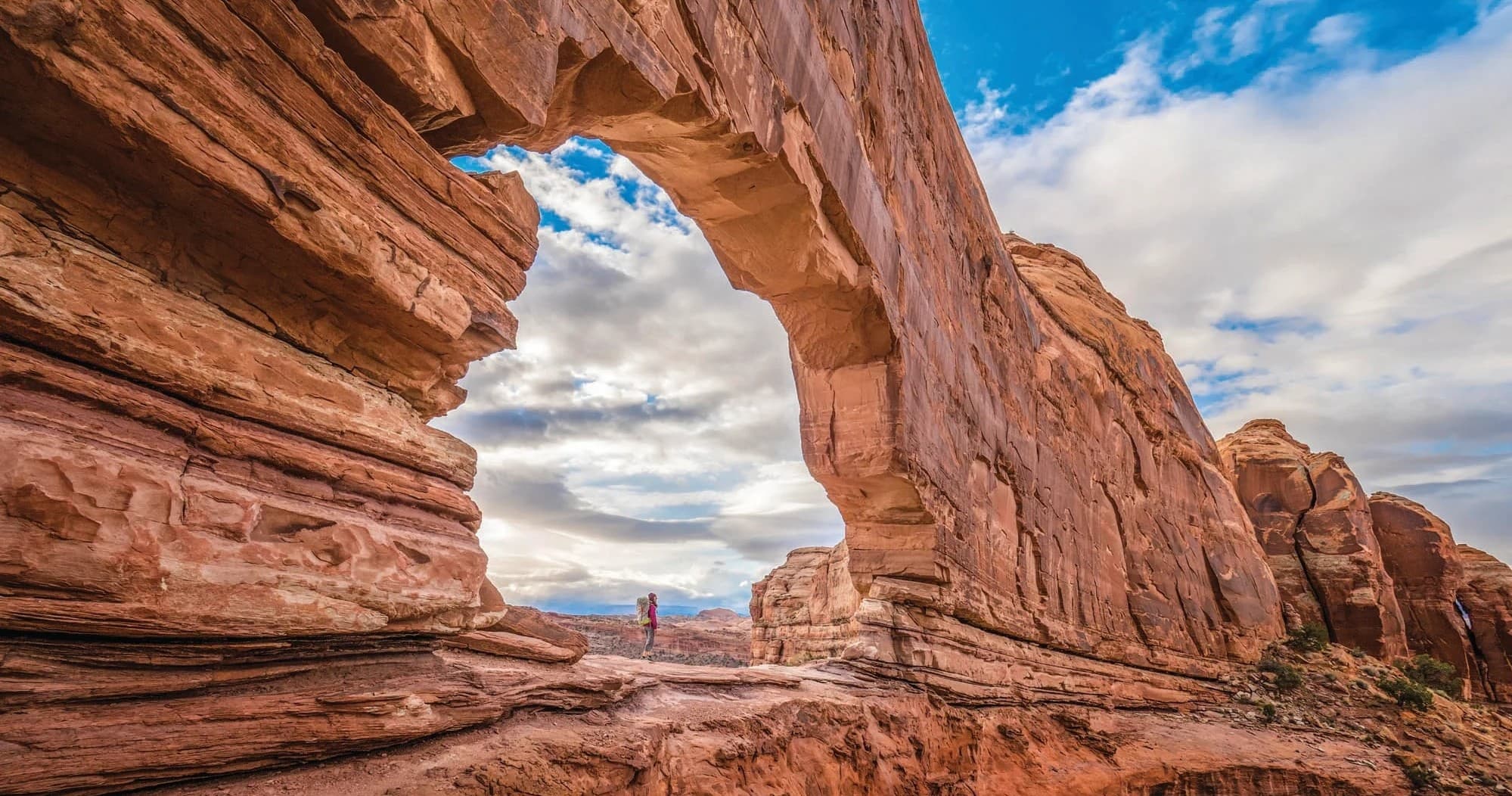 Scenic sandstone arch framing wide desert landscape and sky