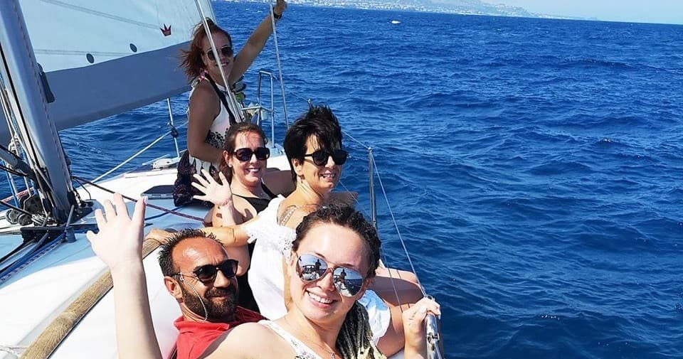 Friends sailing charter smiling on open sea, social boat tour