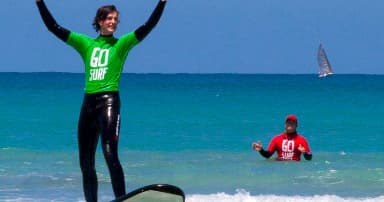 Surfer standing upright on board celebrating in blue ocean