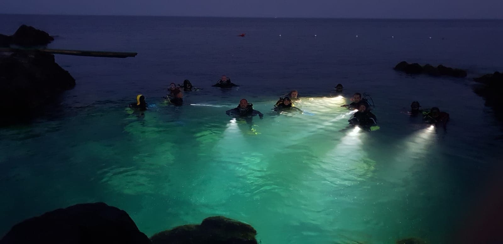 Night scuba divers illuminating reef with underwater lights