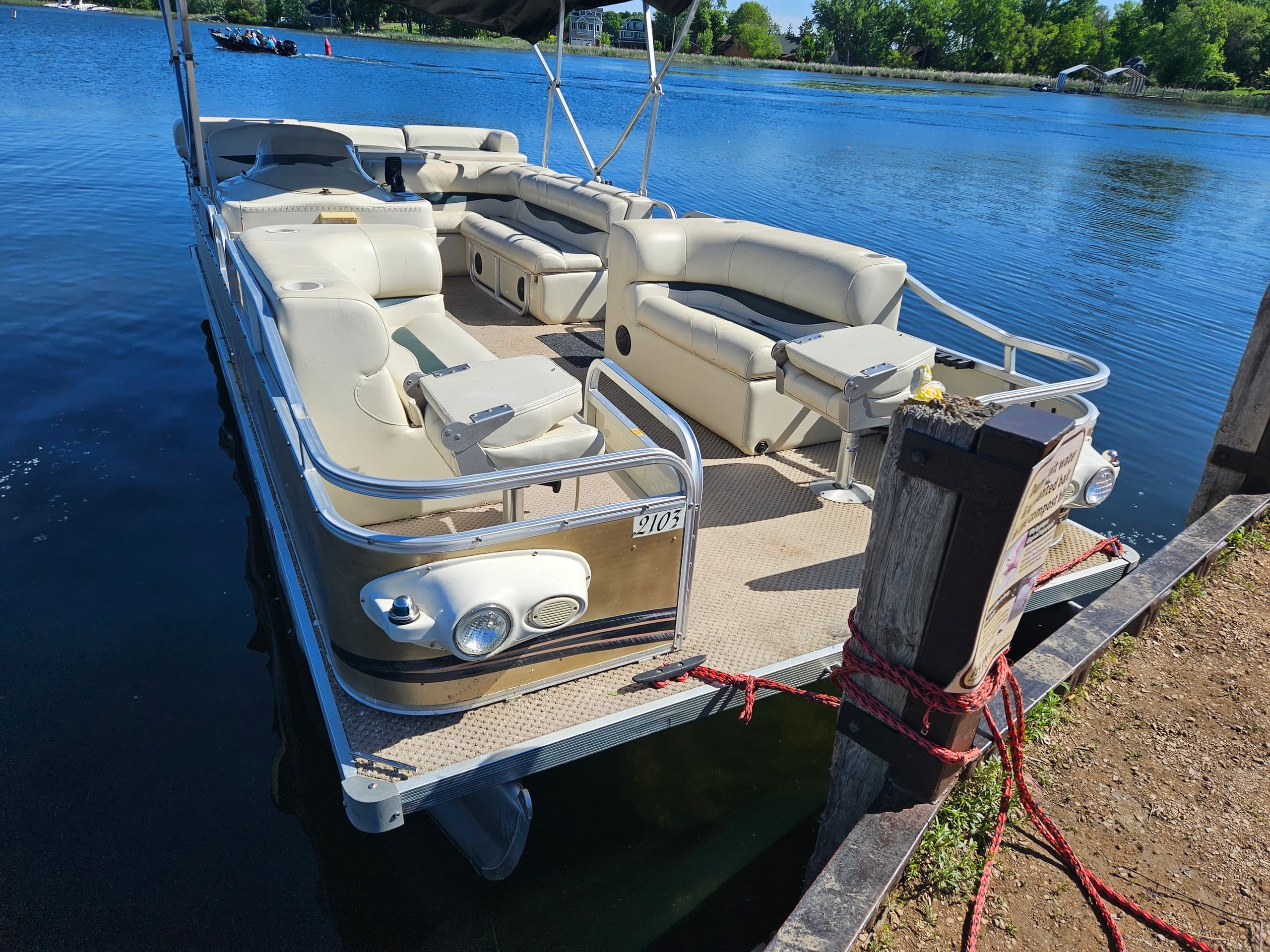 Pontoon boat tied to dock on calm freshwater lake at sunrise