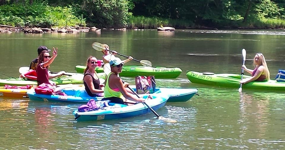 Close-up of colorful kayaks and paddlers socializing on river